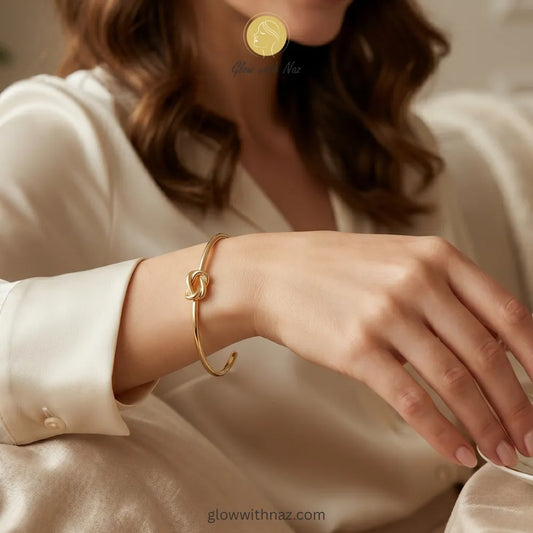 Close-up view of polished gold knot detail on cuff bracelet