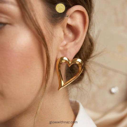 Pair of sleek, polished gold-tone open heart stud earrings against a white background