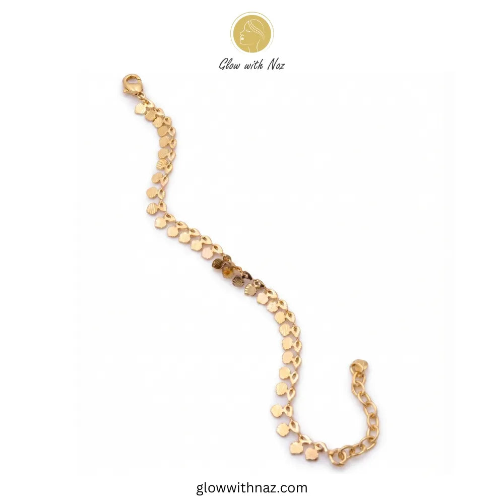 Top-down view of a delicate gold coin anklet clasped in a circle, showcasing its minimalist jewelry aesthetic and textured pendants