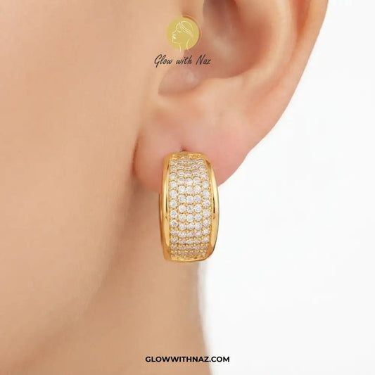 Minimalist Diamond Curvy Hoop Earrings for Girls - Minimalist Diamond Curvy Hoop Earrings for GirlsJewelryGlow With NazGlow With NazE056A close-up of a person's ear wearing a gold hoop earring paved with small clear stones. The brand name 'Glow with Naz' is visible on the image.