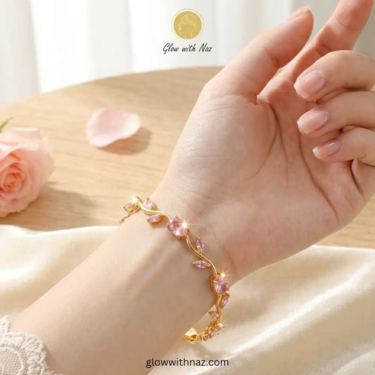 Premium Pink Tulip Bracelet | Rapunzel Floral Stainless Steel Bracelet - Premium Pink Tulip Bracelet | Rapunzel Floral Stainless Steel BraceletJewelryGlow With NazGlow With NazTB005AA gold-toned floral vine bracelet with pink rhinestones worn on a woman's wrist, shown against a soft cream satin fabric and light wood background. The brand name 'Glow with Naz' is visible as an overlay. Tulip Rapunzel bracelet, floral tulip bracelet, Rapunzel inspired jewelry, aesthetic tulip bracelet, trendy charm