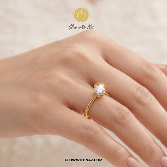 Timeless 4 Grip Diamond Ring for Women - Timeless 4 Grip Diamond Ring for WomenJewelryGlow With NazGlow With NazA close-up of a hand wearing a gold solitaire ring with a clear gemstone. The image features a 'Glow with Naz' logo at the top and the website 'GLOWWITHNAZ. ring, girls rings, rings for girls, rings simple, simple rings, stainless steel jewelry, jewellery set, aesthetic jewelry, simple jewellery, chain, jewelry, artificial jewellery