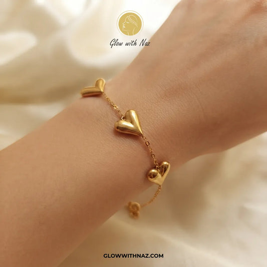 Trio puffed balloon heart gold bracelet worn on model wrist by Glow With Naz