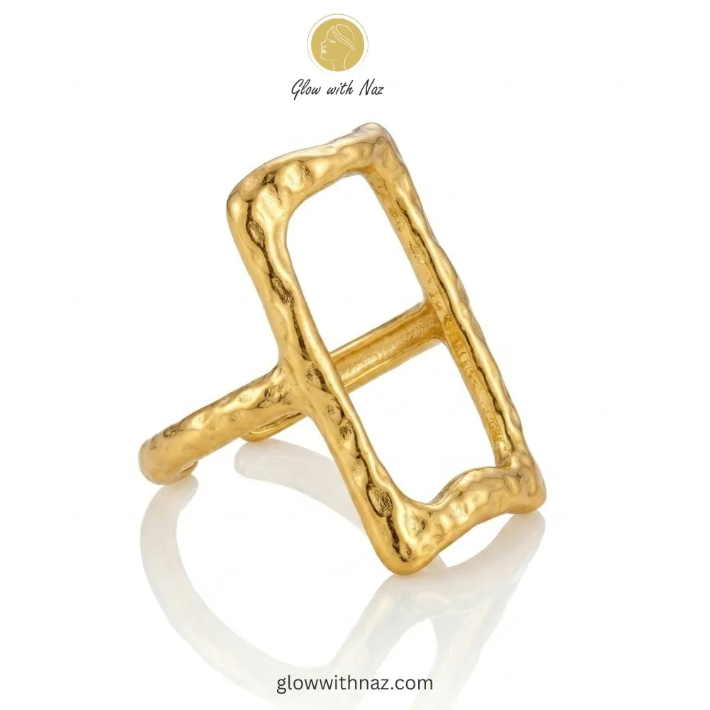 Close-up of a high-polished, hammered-finish gold ring with an open rectangular geometric design.