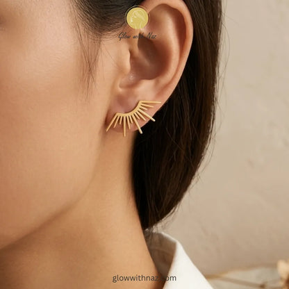 Close-up view of polished gold-tone sunburst ear climbers