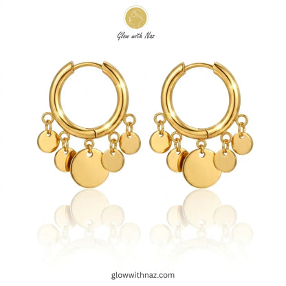 Close-up view of polished gold coin drop earrings on a white background
