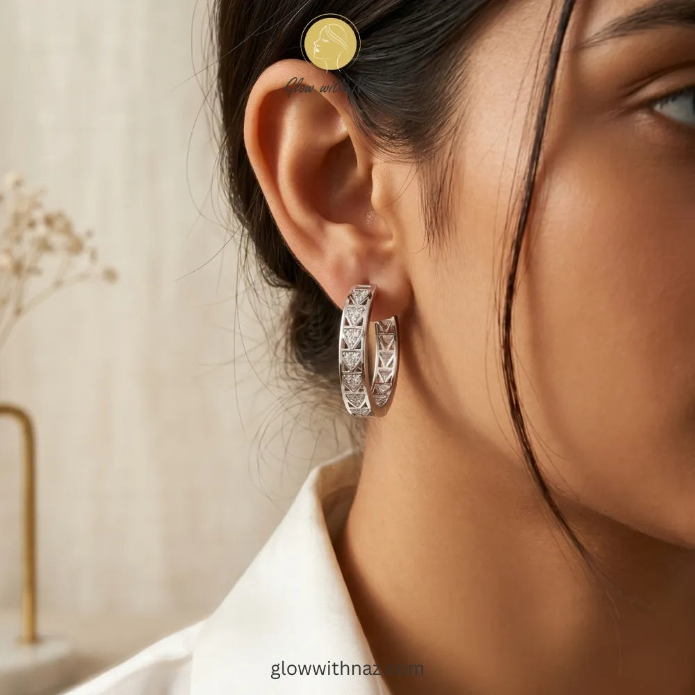 Close-up view of polished silver-tone patterned hoop earrings on a white background