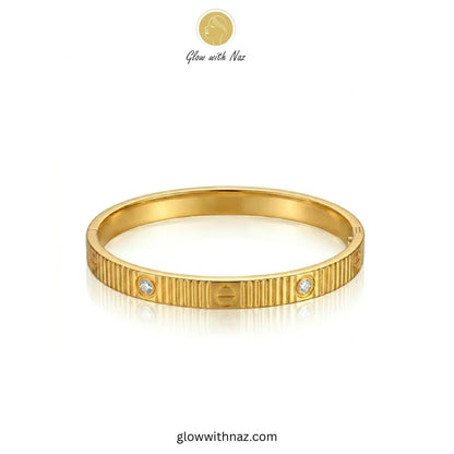 Close-up view of ribbed texture and stones on gold bangle