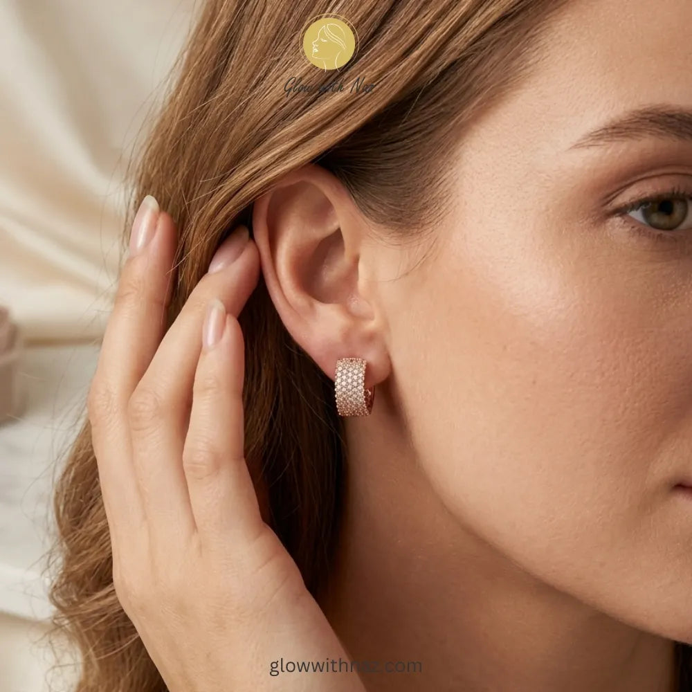 Close-up view of sparkling gold crystal-encrusted hoop earrings on a white background