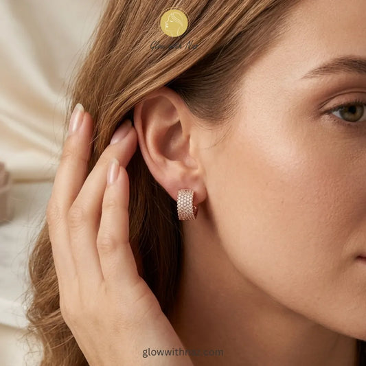 Close-up view of sparkling gold crystal-encrusted hoop earrings on a white background