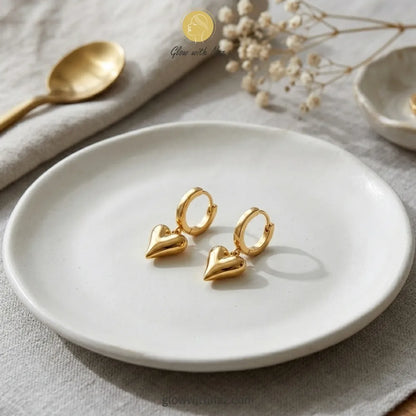Detailed front view of high-shine gold heart drop earrings