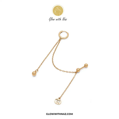 A gold-toned body jewelry piece featuring a small hoop connected to delicate chains with bead details and a small circular charm, displayed on a white background with Glow with Naz branding. helix piercing, cartilage earring, double diamond stud, stainless steel jewelry, body jewelry, viral trending jewelry, ear stack earrings, cartilage piercing jewelry, minimalist piercing, tragus piercing, conch piercing, daith piercing, flat piercing, upper ear piercing, gold stainless steel piercing, sparkling helix st