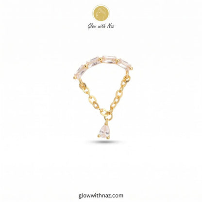 A gold chain bracelet with clear rectangular crystals on the top curve and a dangling clear teardrop crystal, shown on a white background with Glow with Naz branding.