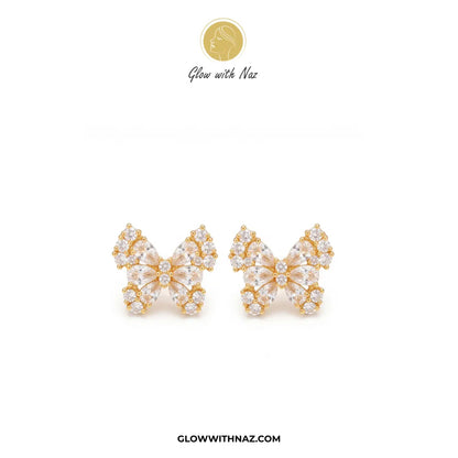 A pair of gold butterfly-shaped stud earrings adorned with clear crystals, displayed on a clean white background with the brand logo 'Glow with Naz' at the top and 'GLOWWITHNAZ.COM' at the bottom.