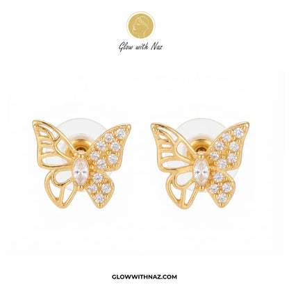 A pair of gold butterfly stud earrings adorned with clear crystals, displayed on a clean white background with the brand logo 'Glow with Naz' at the top and the website 'GLOWWITHNAZ.COM' at the bottom.