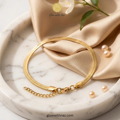 Elegant gold-plated herringbone chain bracelet on model wrist by Glow with Naz