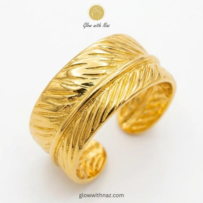 A gold-plated wide cuff ring featuring an intricate feather wrap design, adjustable for a perfect fit.