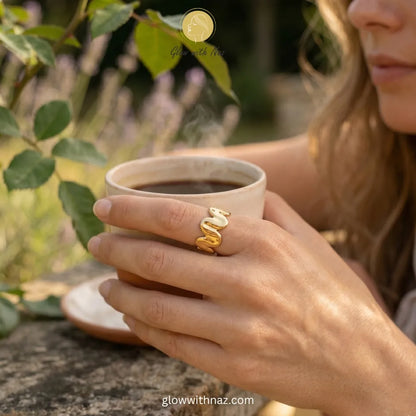 A polished gold ring featuring a molten wave, sculptural design with an adjustable band.