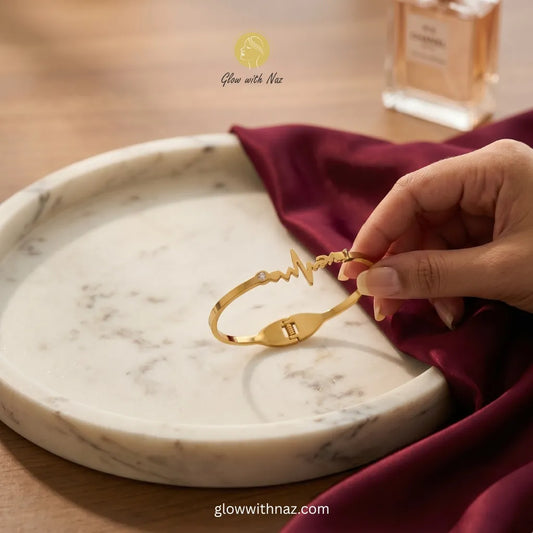 Gold heartbeat ECG bracelet with zircon stone held over marble tray — anti-tarnish stainless steel bangle online in Pakistan by Glow with Naz