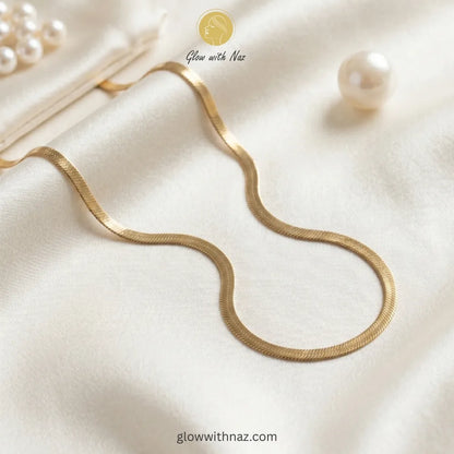 Gold herringbone chain necklace stacked with luxury jewelry accessories