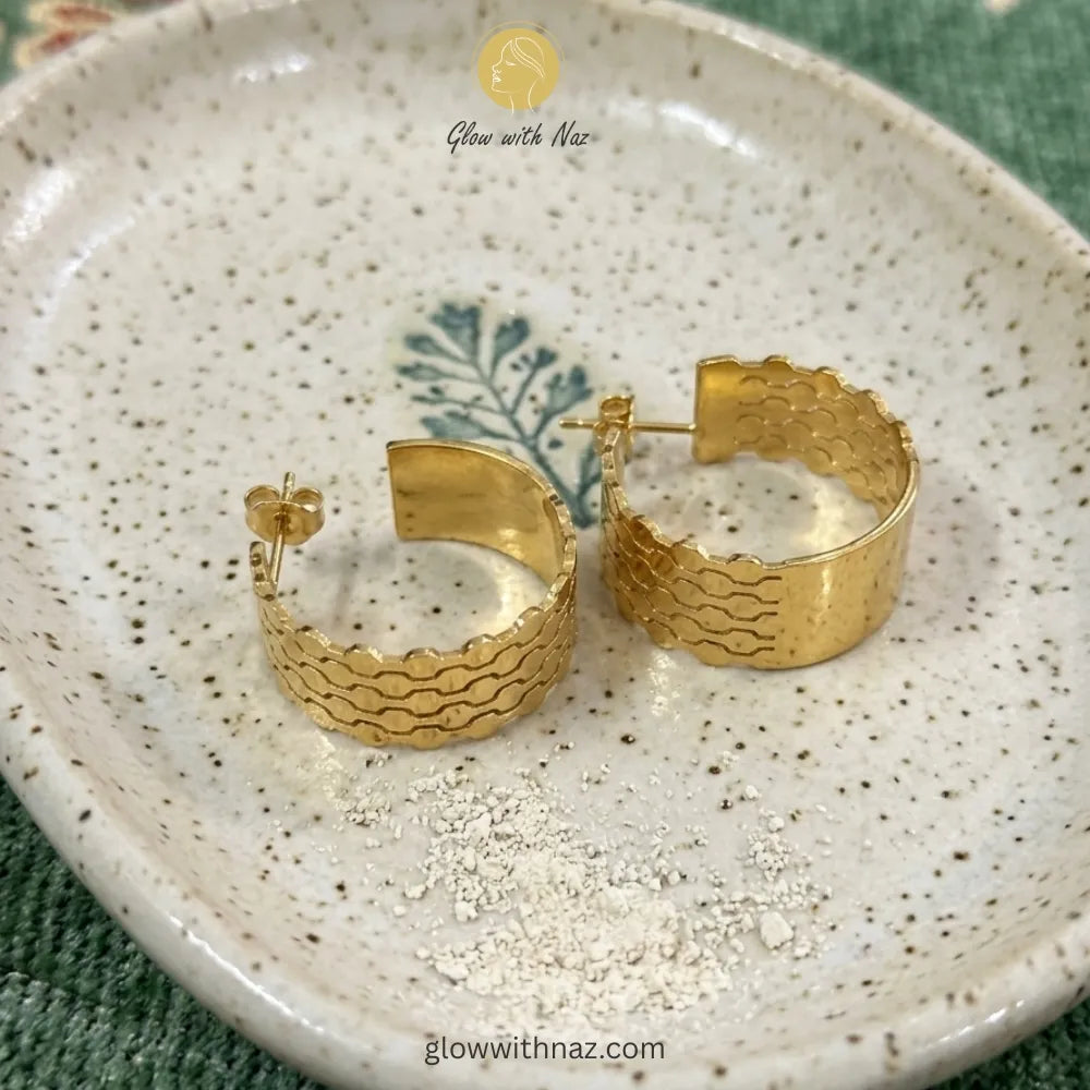 Gold textured hoop earrings displayed to showcase their minimalist shape