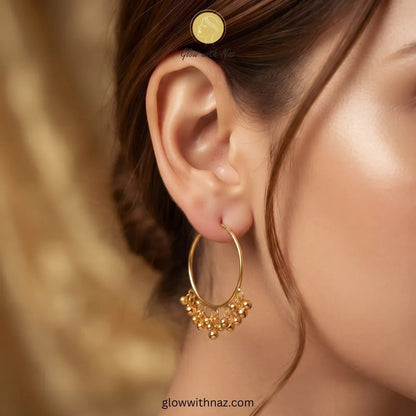 Large gold endless wire hoop earrings featuring dangling polished gold bead fringe by Glow With Naz