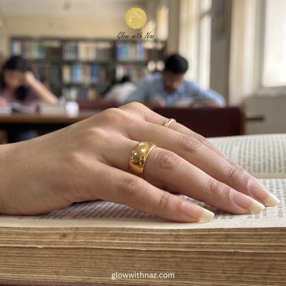 High-end polished gold wide dome band ring displayed on a silk background.