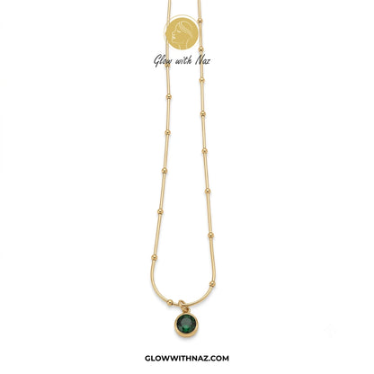 Gold necklace with a green pendant on a white background, branded 'Glow with Naz'. necklace, pendant necklace, necklace set, locket set, simple necklace, pendant set, pendant, chain necklace, diamond pendant, diamond necklace, locket necklace, neck chain, girls locket, heart locket, pendant for girls, necklace for girls, heart necklace, locket for girls, diamond locket, pendant necklace for girls, heart chain locket, stainless steel necklace, double chain necklace, ruby necklace, neck chain for girls, locke