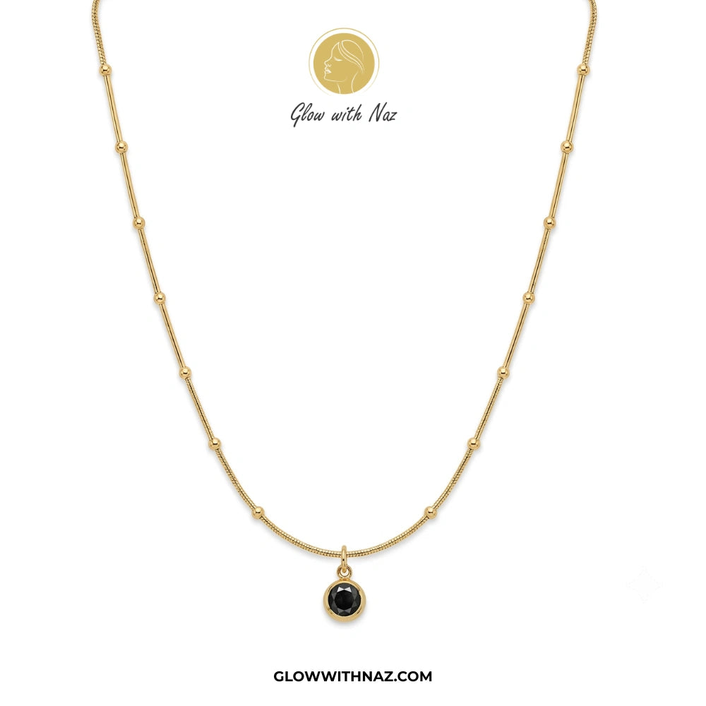 Gold necklace with a black pendant on a white background, branded 'Glow with Naz'. necklace, pendant necklace, necklace set, locket set, simple necklace, pendant set, pendant, chain necklace, diamond pendant, diamond necklace, locket necklace, neck chain, girls locket, heart locket, pendant for girls, necklace for girls, heart necklace, locket for girls, diamond locket, pendant necklace for girls, heart chain locket, stainless steel necklace, double chain necklace, ruby necklace, neck chain for girls, locke