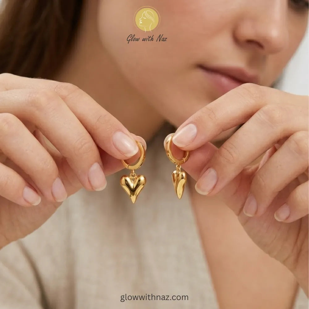Pair of elegant gold-tone hoop earrings with a dangling puffed heart charm
