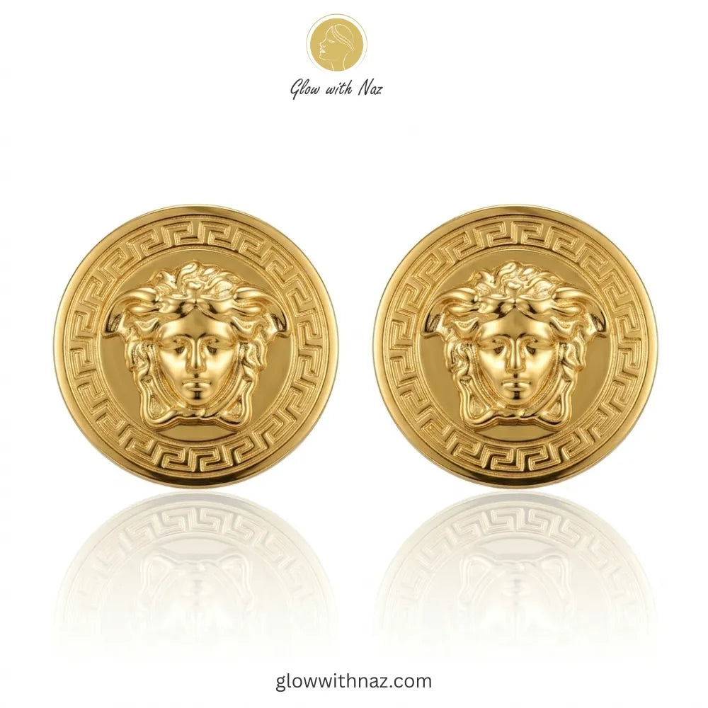Pair of iconic medusa-inspired gold stud earrings with greek key border against white background