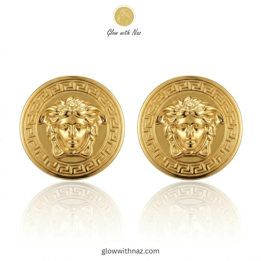 Pair of iconic medusa-inspired gold stud earrings with greek key border against white background