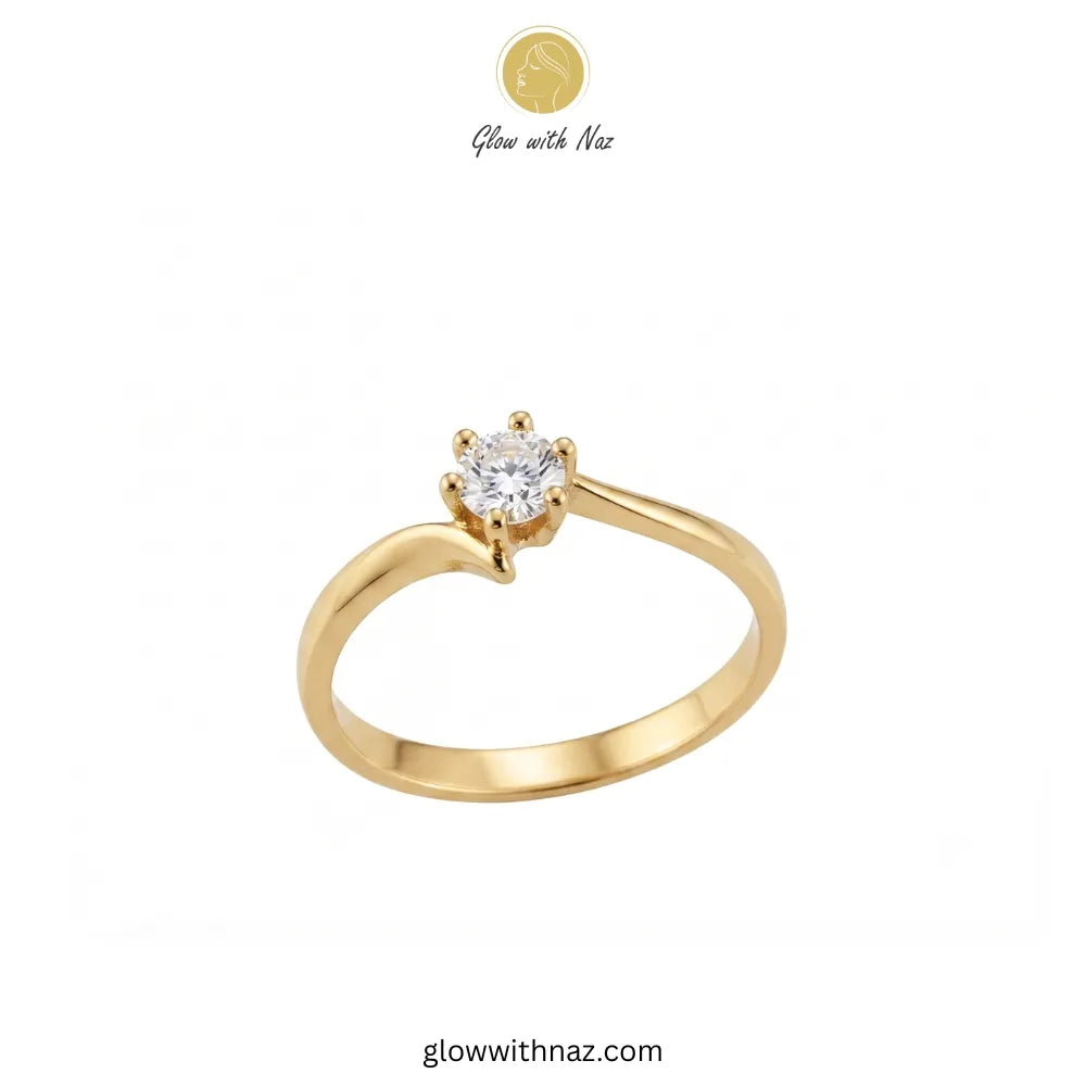 A yellow gold solitaire ring with a round-cut clear gemstone in a four-prong setting, shown on a plain white background with Glow with Naz branding at the top.