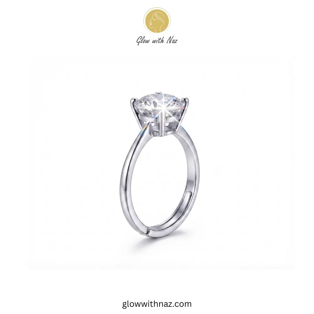 A silver solitaire engagement ring with a round brilliant-cut diamond center stone, shown on a plain white background with the brand logo 'Glow with Naz' at the top.