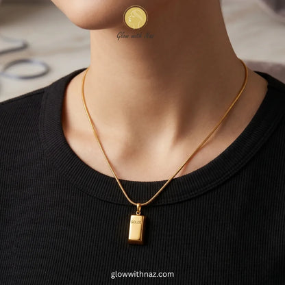 Close-up of gold bar pendant engraving and chain connection