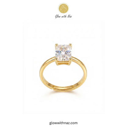 Adjustable Golden Radiant Rectangle Diamond Ring - Adjustable Golden Radiant Rectangle Diamond RingJewelryGlow With NazGlow With NazR021A gold solitaire ring with a square-cut clear gemstone, displayed on a clean white background with a brand logo 'Glow with Naz' at the top. ring, girls rings, rings for girls, rings simple, simple rings, stainless steel jewelry, jewellery set, aesthetic jewelry, simple jewellery, chain, jewelry, artificial jewellery