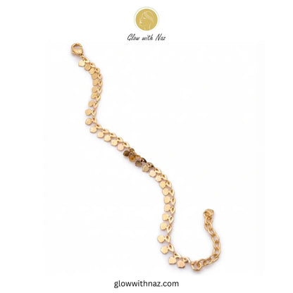 Top-down view of a delicate gold coin anklet clasped in a circle, showcasing its minimalist jewelry aesthetic and textured pendants