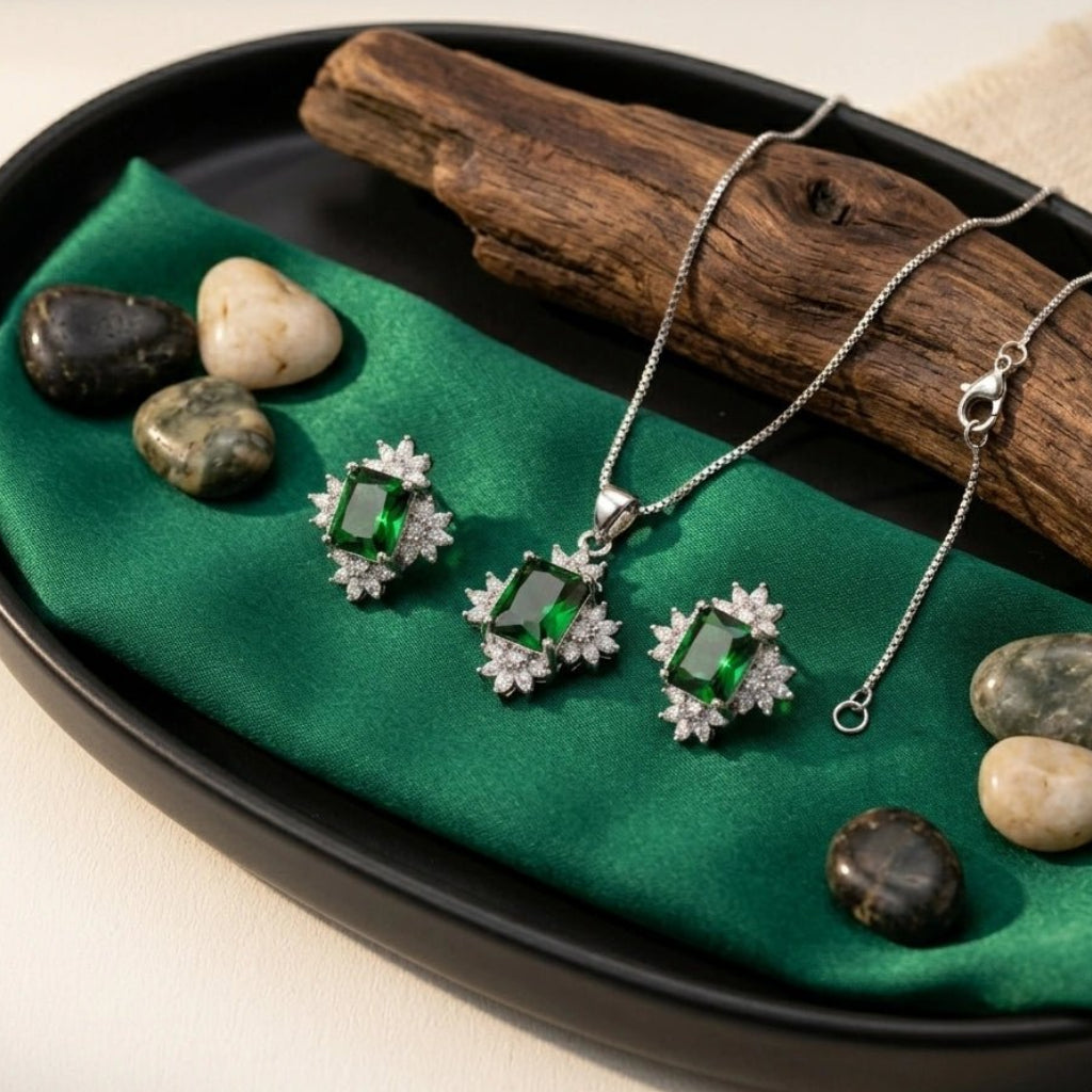 Elegant Sun Flower Style Necklace & Earrings Set - Elegant Sun Flower Style Necklace & Earrings SetJewelryGlow With NazGlow With NazN-N012N-N012Elegant silver jewelry set featuring an emerald - cut green crystal pendant necklace and matching stud earrings, both surrounded by a sparkling cubic zirconia floral halo, displayed on a green silk fabric