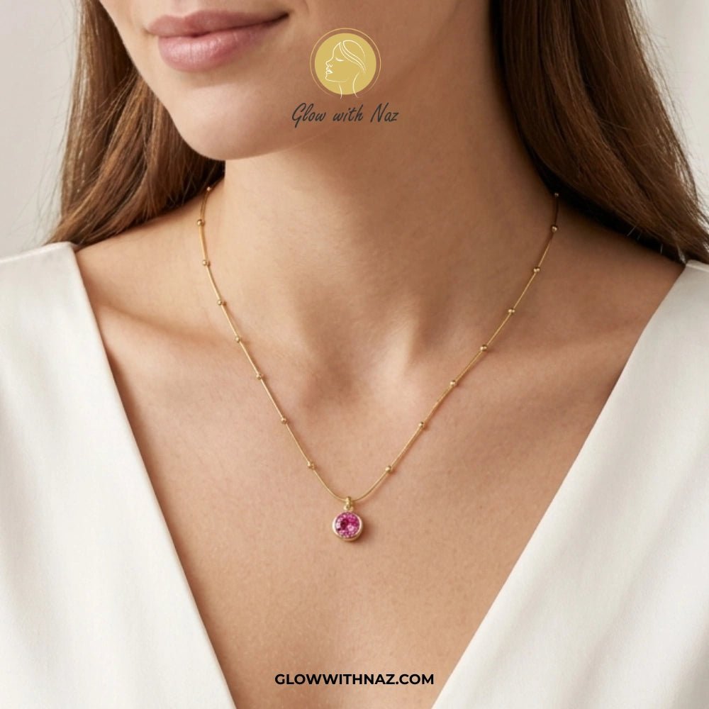 Gold Plated Stainless Steel Beaded Chain Pink Pendant Necklace - Gold Plated Stainless Steel Beaded Chain Pink Pendant NecklaceJewelryGlow With NazGlow With NazGold necklace with a pink gemstone worn by a model, with 'Glow with Naz' branding. necklace, pendant necklace, necklace set, locket set, simple necklace, pendant set, pendant, chain necklace, diamond pendant, diamond necklace, locket necklace, neck chain, girls locket, heart locket, pendant for girls, necklace for girls, heart necklace, l