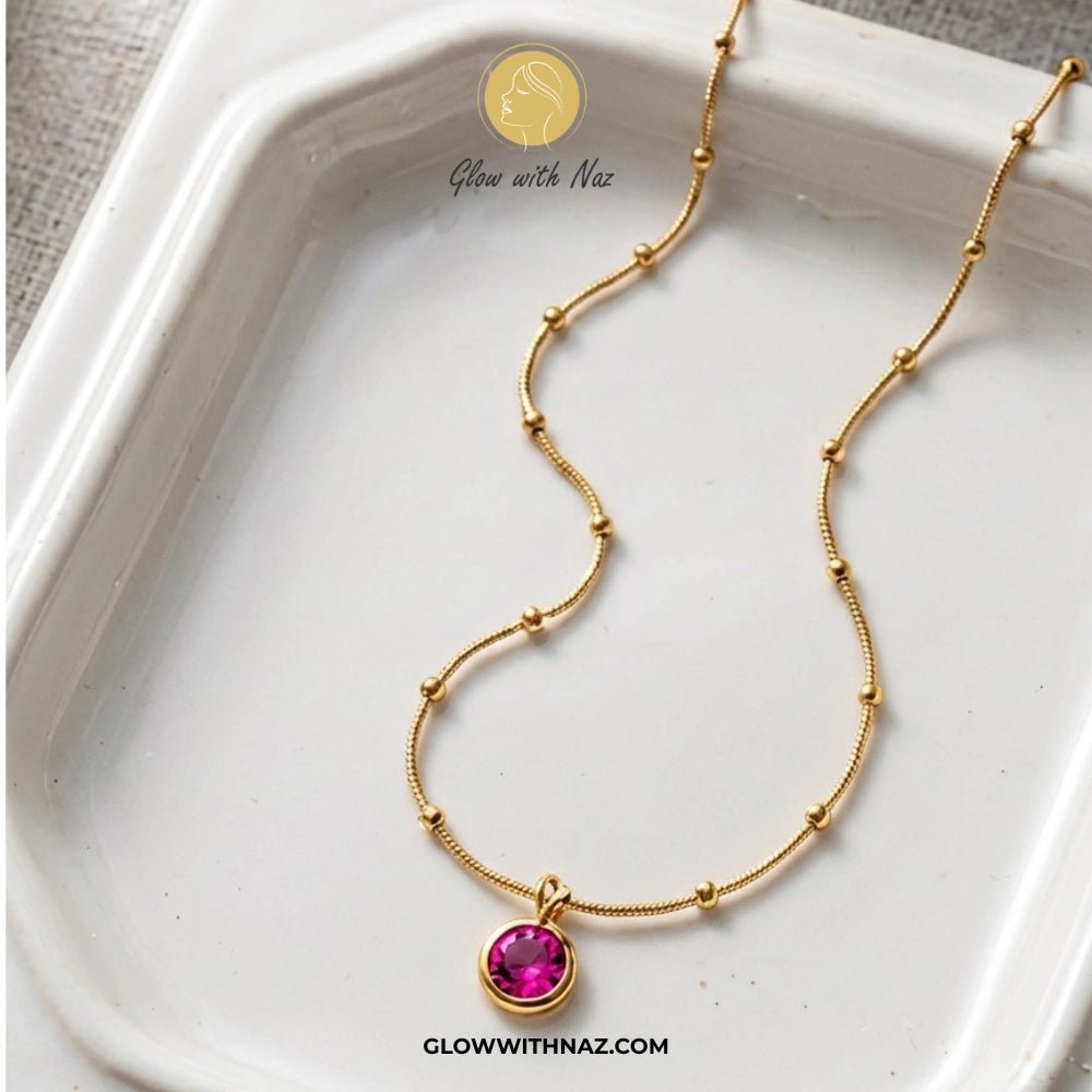 Gold Plated Stainless Steel Beaded Chain Pink Pendant Necklace - Gold Plated Stainless Steel Beaded Chain Pink Pendant NecklaceJewelryGlow With NazGlow With NazGold necklace with a pink gemstone pendant on a white dish, branded 'Glow with Naz'. necklace, pendant necklace, necklace set, locket set, simple necklace, pendant set, pendant, chain necklace, diamond pendant, diamond necklace, locket necklace, neck chain, girls locket, heart locket, pendant for girls, necklace for girls, heart necklace,
