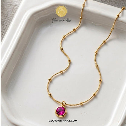 Gold Plated Stainless Steel Beaded Chain Pink Pendant Necklace - Gold Plated Stainless Steel Beaded Chain Pink Pendant NecklaceJewelryGlow With NazGlow With NazGold necklace with a pink gemstone pendant on a white dish, branded 'Glow with Naz'. necklace, pendant necklace, necklace set, locket set, simple necklace, pendant set, pendant, chain necklace, diamond pendant, diamond necklace, locket necklace, neck chain, girls locket, heart locket, pendant for girls, necklace for girls, heart necklace,