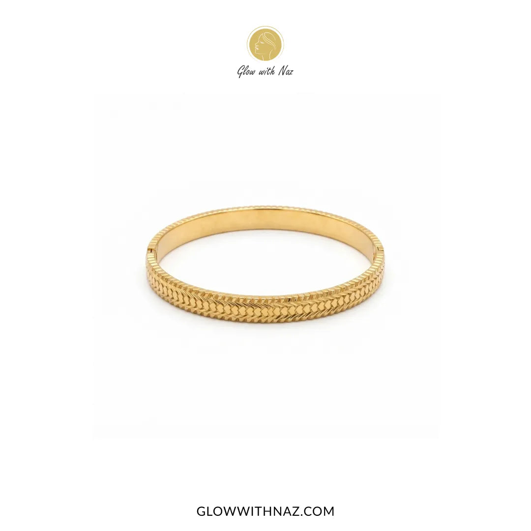 Gold heart line textured hinge cuff bangle displayed on marble platter by Glow With Naz