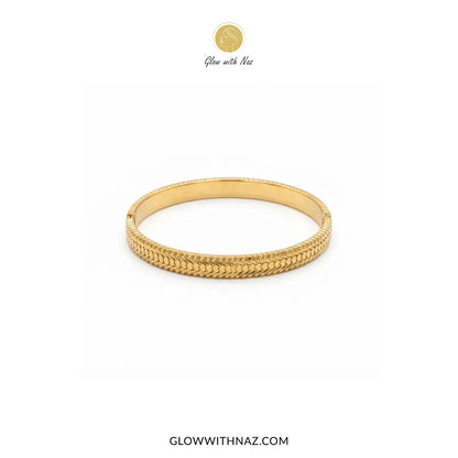 Gold heart line textured hinge cuff bangle displayed on marble platter by Glow With Naz