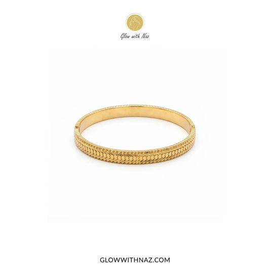 Gold heart line textured hinge cuff bangle displayed on marble platter by Glow With Naz