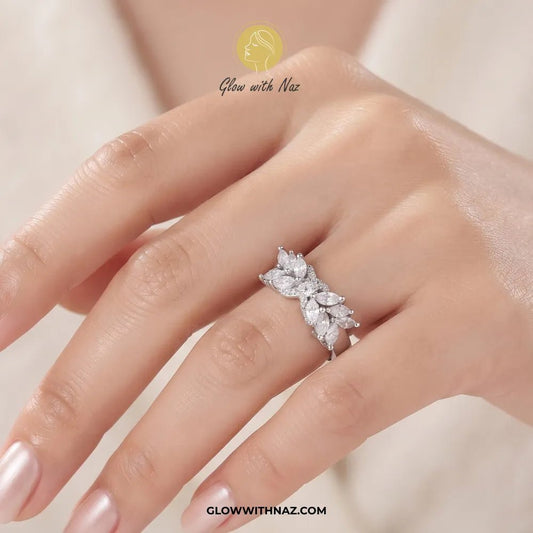 Marquise Leaf "X" Cross Adjustable Ring - #Marquise Leaf "X" Cross Adjustable RingJewelryGlow With NazGlow With NazR0043-R0044SilverA silver-tone ring with a bow-like cluster of clear gemstones, shown on a plain white background. The brand name 'Glow with Naz' appears at the top with a gold emblem, and 'glowwithnaz.#