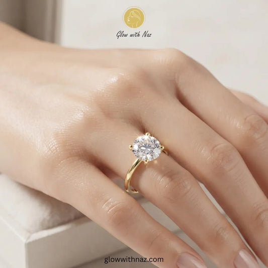 Minimal Golden Round Diamond Adjustable Statement Ring for Her - Minimal Golden Round Diamond Adjustable Statement Ring for HerJewelryGlow With NazGlow With NazR019A close-up of a hand wearing a yellow gold solitaire ring with a clear round-cut gemstone. The brand logo 'Glow with Naz' is visible at the top of the image. ring, girls rings, rings for girls, rings simple, simple rings, stainless steel jewelry, jewellery set, aesthetic jewelry, simple jewellery, chain, jewelry, artificial jewellery