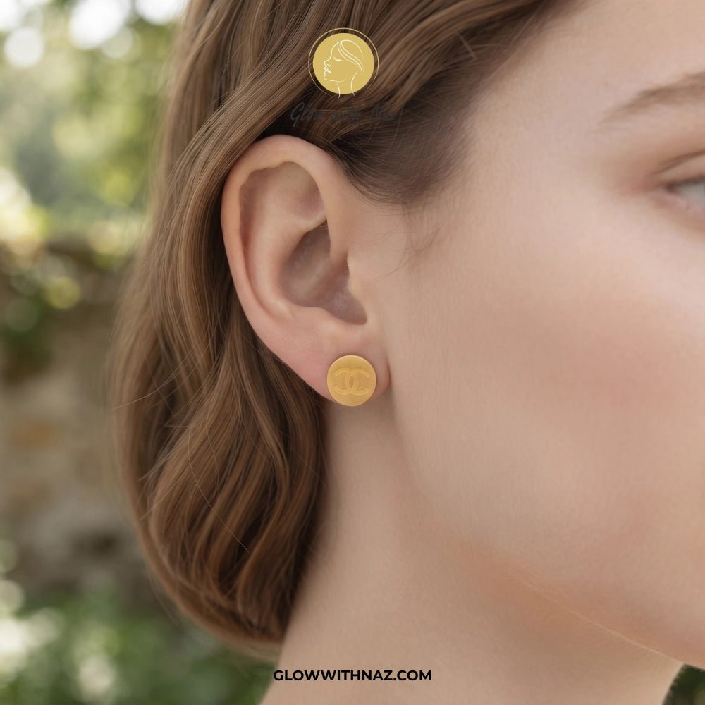 Minimal Stainless Steel Channel Coin Stud Earring - Minimal Stainless Steel Channel Coin Stud EarringJewelryGlow With NazGlow With NazE043A close-up of a woman's ear wearing a small round gold stud earring, with a matching gold hair clip visible in her hair. The background is softly blurred outdoor greenery. studs earrings, small earrings, girls earrings, simple earrings, earrings for girls, black earrings, earrings, ear rings, earrings tops, stud earrings, tops earrings, aesthetic earrings, hoo