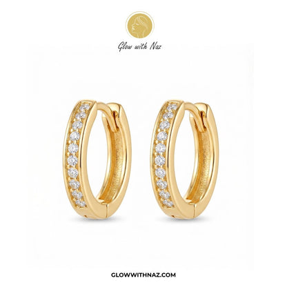 Premium Gold Plated Glass Crystal Hoops for Women - Premium Gold Plated Glass Crystal Hoops for WomenJewelryGlow With NazGlow With NazE040A pair of gold huggie hoop earrings with a row of clear pavé stones on the front, displayed on a clean white background with the brand logo 'Glow with Naz' at the top and the website 'GLOWWITHNAZ.COM' at the bottom. studs earrings, small earrings, girls earrings, simple earrings, earrings for girls, black earrings, earrings, ear rings, earrings tops, stud earr
