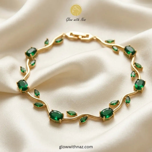 Premium Green Tulip Bracelet | Rapunzel Floral Stainless Steel Bracelet - Premium Green Tulip Bracelet | Rapunzel Floral Stainless Steel BraceletJewelryGlow With NazGlow With NazTB003AA gold leaf-shaped bracelet adorned with green marquise and oval gemstones, displayed on a draped cream satin fabric. The brand logo 'Glow with Naz' is visible at the top. Tulip Rapunzel bracelet, floral tulip bracelet, Rapunzel inspired jewelry, aesthetic tulip bracelet, trendy charm bracelet, stainless steel tuli