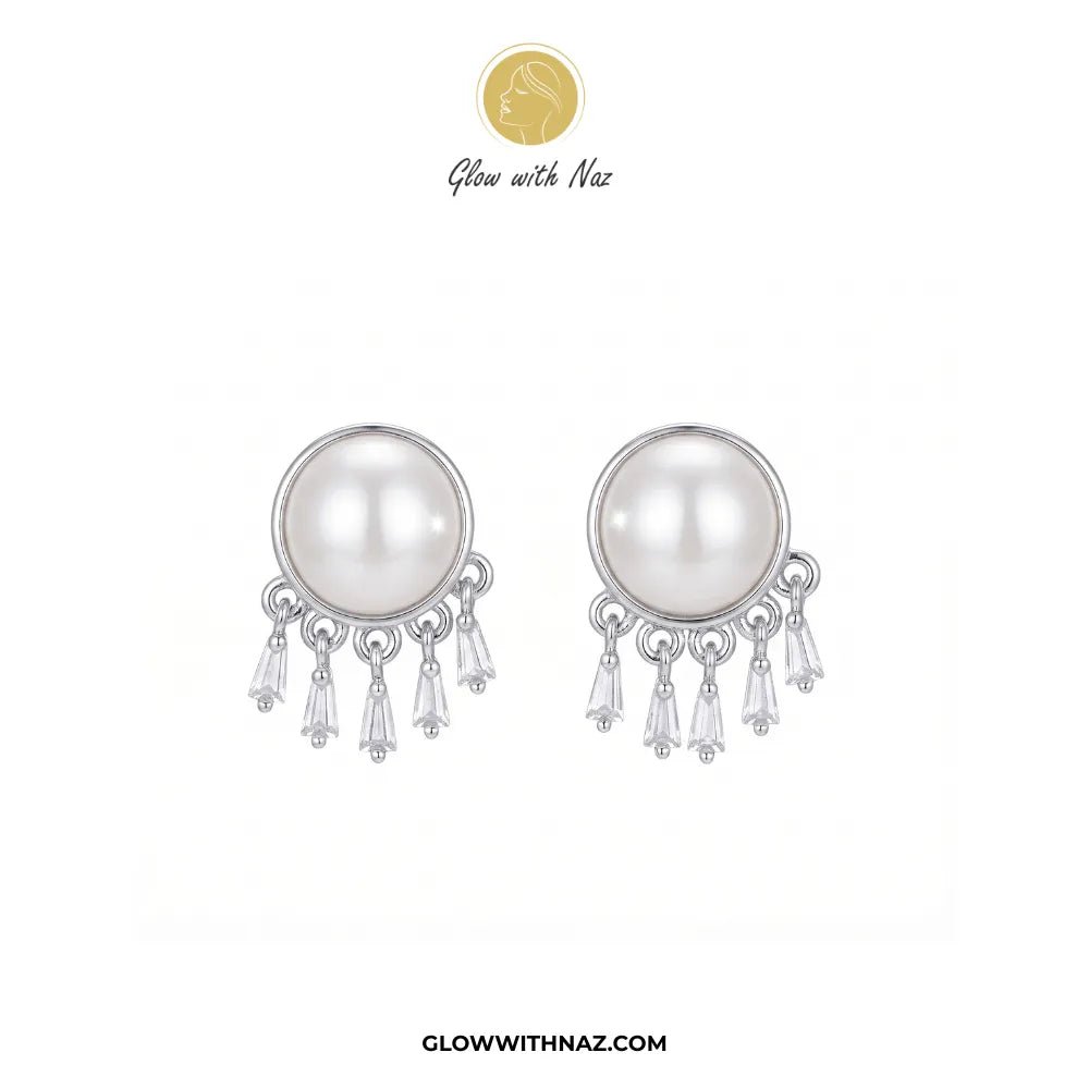 Radiant Mini Silver Pearl Stud Earring - #Radiant Mini Silver Pearl Stud EarringJewelryGlow With NazGlow With NazE087A pair of silver-toned dangle earrings featuring a large white pearl in a round bezel setting, with three clear crystal drops hanging below. The brand logo 'Glow with Naz' is displayed at the top, and the website 'GLOWWITHNAZ.#